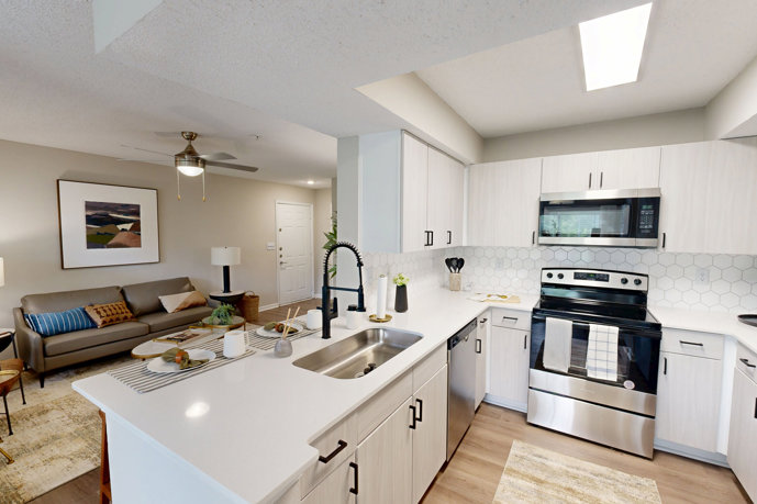 Brightly lit white apartment kitchen with stainless steel appliances
